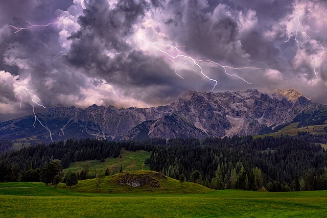 Bild von Gewitterwolken mit Blitz über Bergen und Wiesen